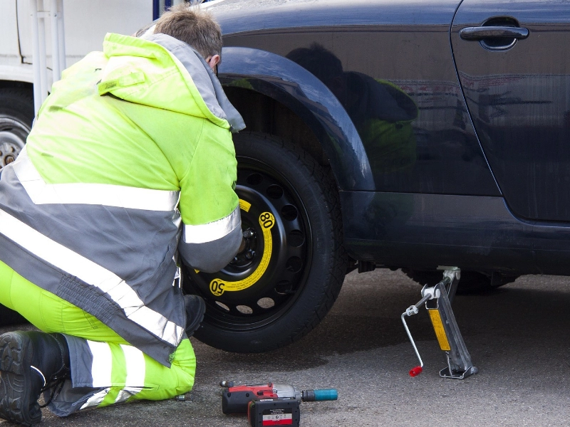 A person replacing a tire on a car